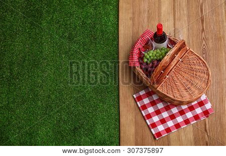 Picnic Basket With Wine And Grapes On Wooden Surface Outdoor, Top View. Space For Text