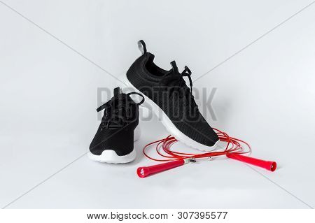 Black Sports Running Shoes With White Sole And Red Jumping Rope Isolated On White Background. Concep