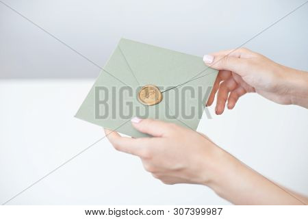 Close-up Photo Of Female Hands Holding A Silver Blue Or Pink Invitation Envelope With A Wax Seal, A 