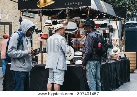 London, Uk - June 15, 2019: Man Buying Hats At Stall Inside Spitalfields Market, One Of The Finest S