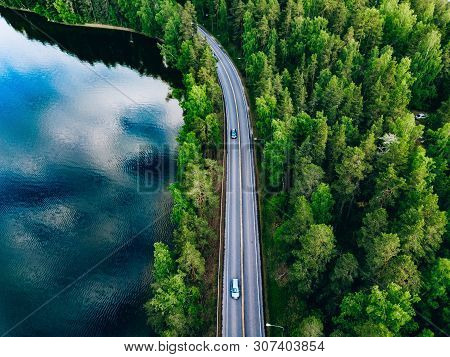 Aerial View Of Road Between Green Forest And Blue Lake In Finland