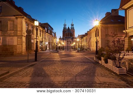 Gniezno In Poland, Evening View Of Street In Old Town With The Royal Gniezno Cathedral In The Backgr