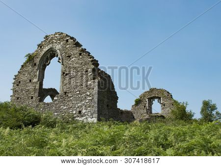 View Of Stone Church Ruins Showing Twin Window Arches On Top Of Grass Hill With Blue Sky