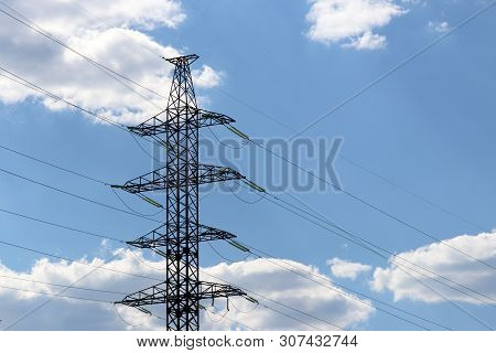 High Voltage Power Line Supports With Electrical Wires On Blue Sky With White Clouds. Electricity Tr