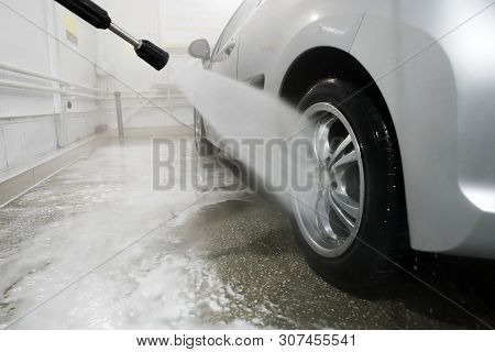 Man Cleaning Vehicle With High Pressure Water Spray Or Jet. Car Wash Details. Wash The Wheels With W