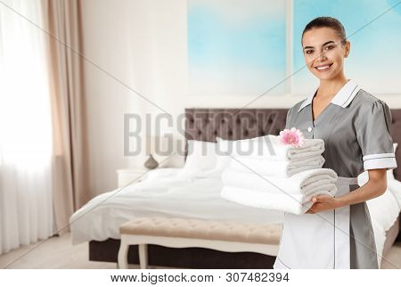 Chambermaid With Stack Of Fresh Towels In Hotel Room. Space For Text