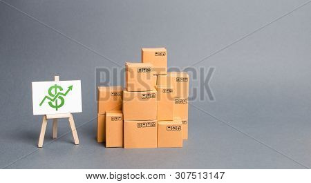 Lots Of Cardboard Boxes And Stand With Green Up Arrow. Growth Of Income From The Sale Of Goods. Pric