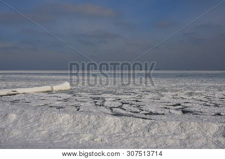 Frozen Black Sea Near The Coast With Snow, Split Ice Floes And Ice-covered Pier In The Foreground An
