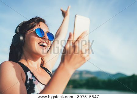 Young Beautiful Female Jogging And Listening To Music Using Smartphone And  Wireless Headphones Chee