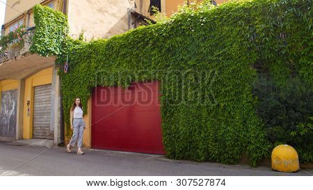 Young Woman Walking Through The Streets Past The Green Wall