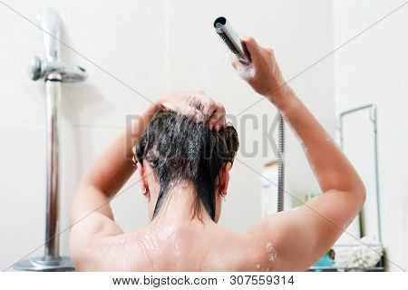 Woman Washing Her Hair With A Lot Of Foam Inside A Shower. Back View Of Young Woman Washing Her Hair
