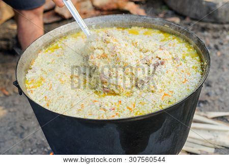 Cooking Tasty Pilaf In Nature. Cooking Pilaf In Big Cauldron On Fire At Picnic. Cooking Pilaf In A P