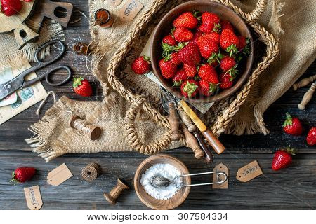 Overhead Shot Of Tasty Ripe Strawberries In Wooden Bowl Stands In Wicker Strawy Basket On Rustic Tab