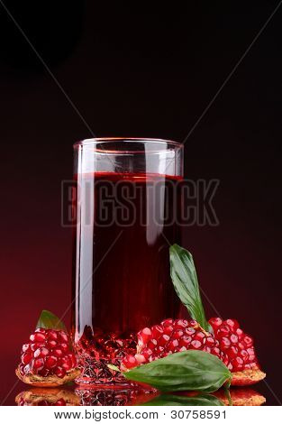 rijpe pomergranate en glas sap op rode achtergrond