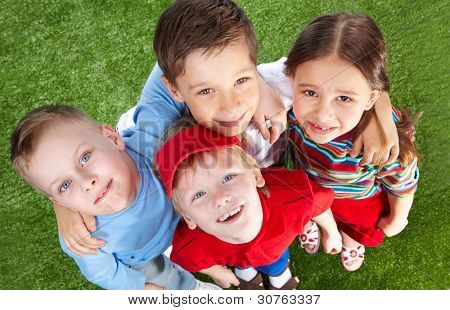 Smiling children spending time together at lawn and looking at cam