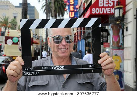 6-18-2019 Hollywood, California: A man wears silver reflective sunglasses while posing with a Hollywood Movie Click Board while on the streets on Hollywood California. Editorial Use Only. 