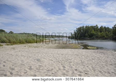 Wide Blue River Is Slow Flowing. Summer. Sunny Weather And White Sand. Green Trees Far Away