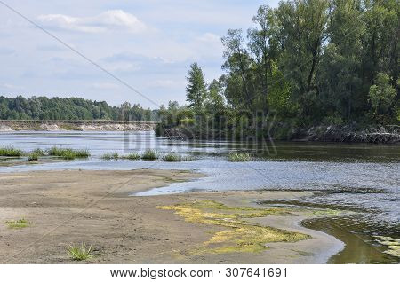 Wide Blue River Is Slow Flowing. Summer. Sunny Weather And White Sand. Green Trees Far Away