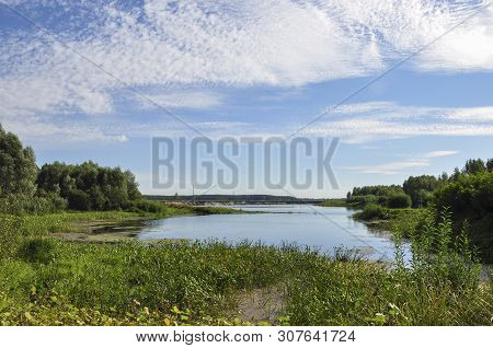 Wide Blue River Is Slow Flowing. Summer. Sunny Weather And White Sand. Green Trees Far Away