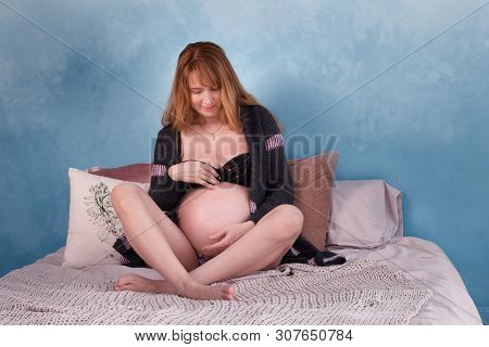 Expectant Motheris Lying On The Bed, Smiling, Looking At The Belly In Which Her Future Child Is
