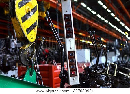 Bridge Lifting Crane Hook Against The Background Of The Assembly Line Industrial Factory. The Concep