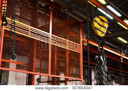 Bridge Lifting Crane Hook Against The Background Of The Assembly Line Industrial Factory. The Concep
