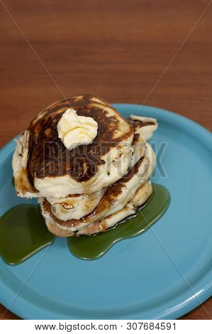 Stack Of Pancakes Topped With Butter And Slathered In Syrup