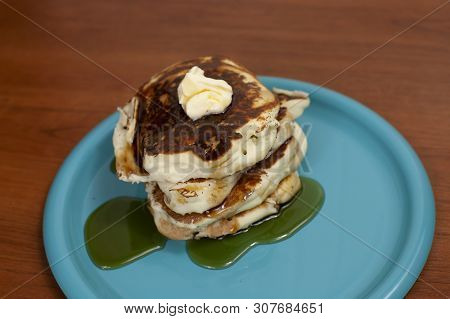 Stack Of Pancakes Topped With Butter And Slathered In Syrup