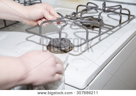 Woman Wiping Down A Stove With A Paper Towel