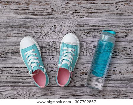 Turquoise Sneakers With Pink Soles And A Water Bottle On The Wooden Floor. Sports Style. Flat Lay. T