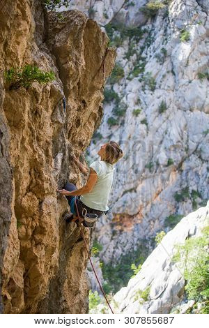 Rock Climbing And Mountaineering In The Paklenica National Park. A Woman Overcomes A Challenging Cli