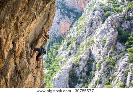 Rock Climbing And Mountaineering In The Paklenica National Park. A Woman Overcomes A Challenging Cli