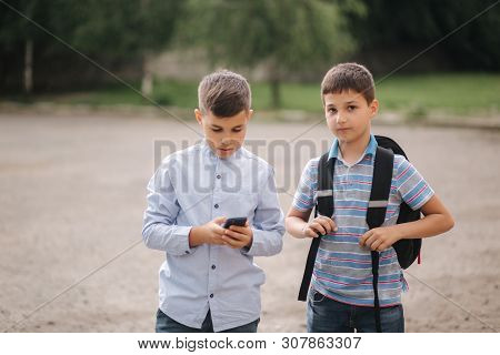 Two Boys Plays Online Games After School Classes. Young Boys Smile And Use Phone