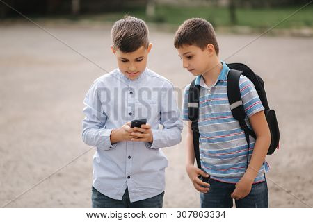 Two Boys Plays Online Games After School Classes. Young Boys Smile And Use Phone