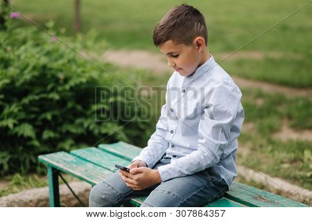 Young Boy Sitting On The Bench And Play Online Games During School Break