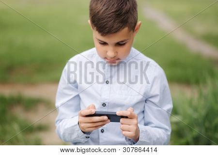Young Boy Sitting On The Bench And Play Online Games During School Break