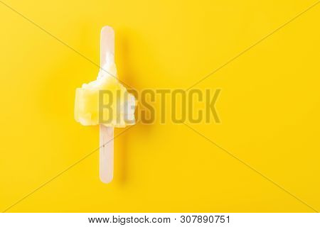 Top View Yellow Popsicle With The Last Bit On A Yellow Background With Copy Space