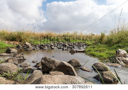 Shallow River Flowing Near The Remnants Of The Early Bronze Age Megalithic Complex Of The Early Bron