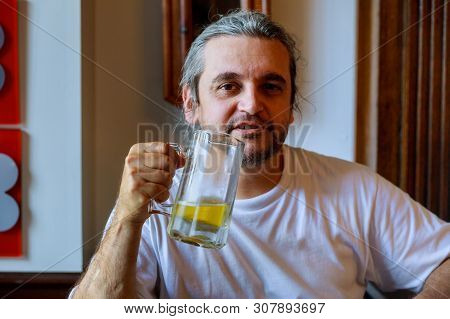Young Man Drinking Beer In Glass Bock, Could Be Student Or Alcoholic.