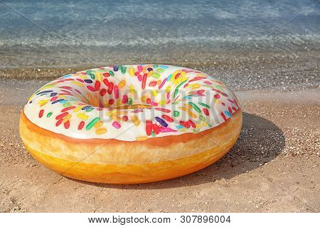 Bright Inflatable Doughnut Ring Near Sea On Sunny Day