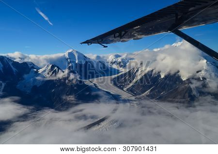 Aerial View Of Alaska Mountaion Range Around Denali Peak From A Plane With Glaciers Around And Blue 
