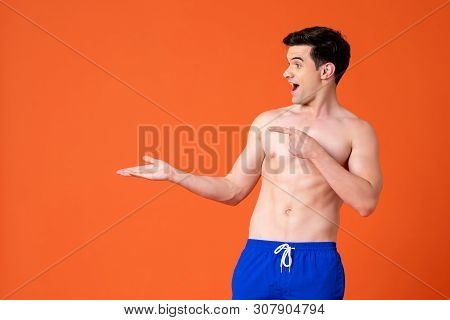 Excited Shirtless Handsome Man Opening Hand On Colorful Orange Background With Copy Space For Summer