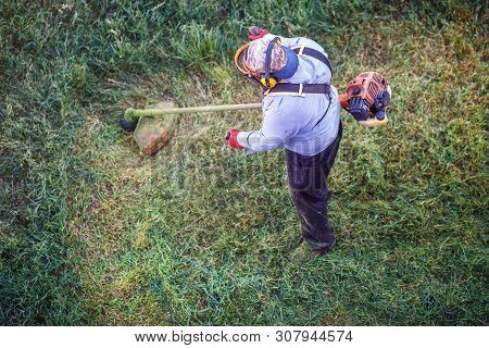 Top View Fat Dirty Lawnmover Man Worker Cutting Dry Grass With Lawn Mower.