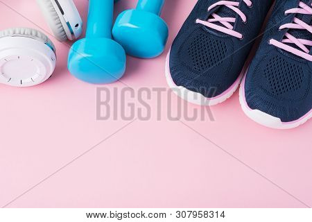 Female Sport Shoes, Blue Dumbbells Andwhite Headphones On Pink Background With Copy Space, Top View