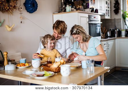 Young Parents With Newborn Baby And Small Toddler Son At Home.