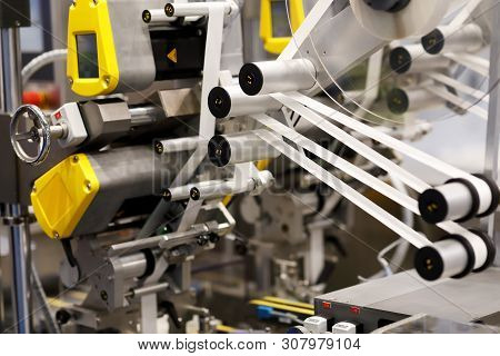 Closeup View Of Industrial Automatic Self Adhesive Labeling Machine. Selective Focus.