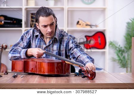 Young handsome repairman repairing cello