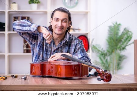 Young handsome repairman repairing cello