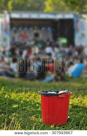 Red Litter On Green Grass. Garbage In The Nature After The Concert.