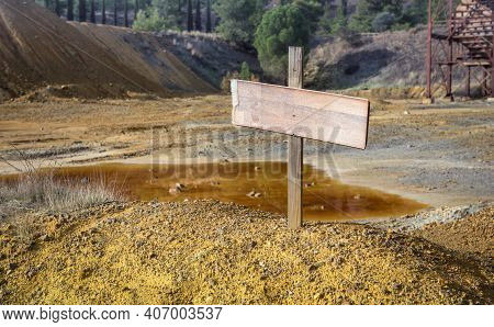 Blank Sign On Top Of Chemical Waste Pile With An Abandoned Mine Quarry And Rusty Machinery, Selectiv